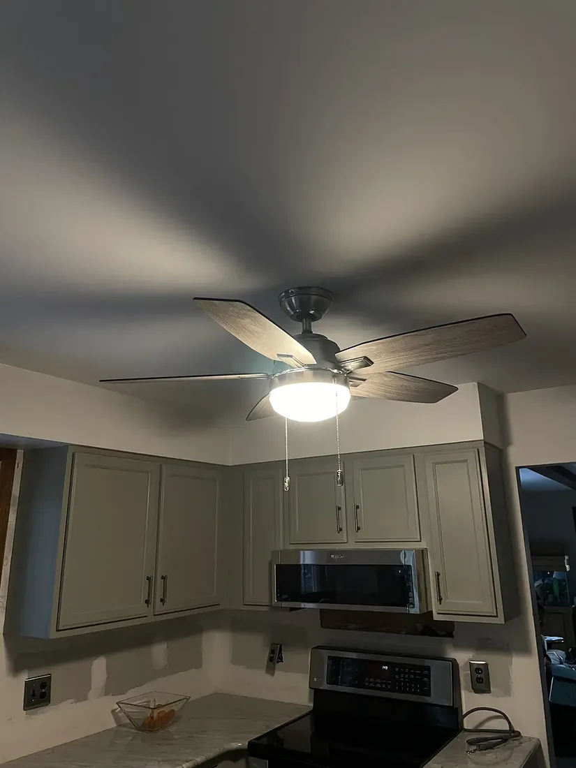 A ceiling fan with a light kit installed in a remodeled kitchen