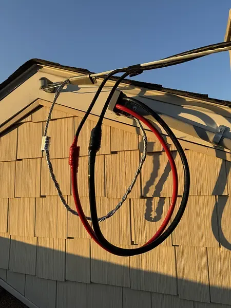 Overhead service conductors with drip loops connected at the gable of a shingled house