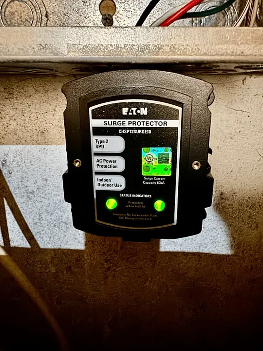 An Eaton Type 2 whole-home surge protector mounted below a panel with both green status lights on
